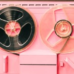 Pink retro tape-recorder device, tape deck or music player with reel tape discs. Old-fashioned radio machine with cassettes or cartridges used for radio data storing